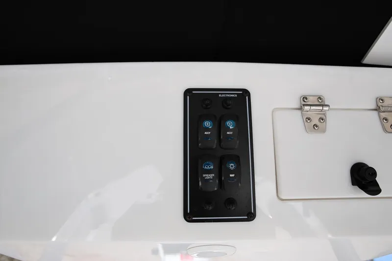 Slide: The Image of 2025 Stingray 216 CC boat control panel with electronic switches and storage compartment. - 14