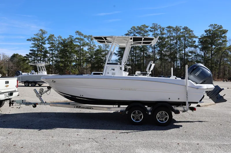 Slide: The Image of 2025 Stingray 216 CC boat on trailer, parked outdoors with trees in background. - 4