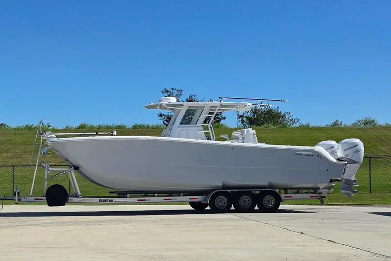 Slide: The Image of 2022 Invincible 33 Catamaran on trailer, parked in driveway near house. - 2