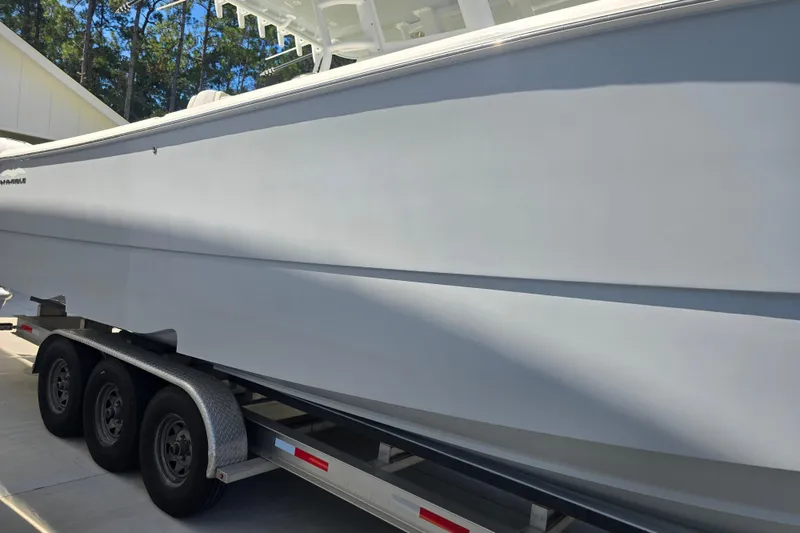 Slide: The Image of 2022 Invincible 33 Catamaran on trailer, parked outdoors with trees in background. - 6