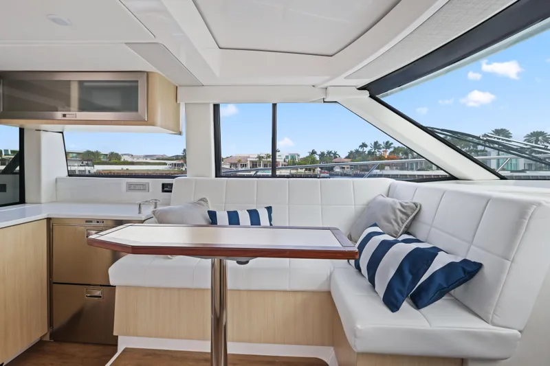 Slide: The Image of 2024 Regal 38 XO yacht interior with white seating, striped cushions, and a sleek dining table. - 15