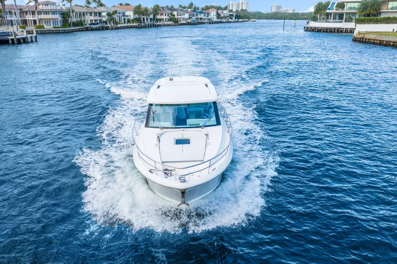 Slide: The Image of 2024 Regal 38 XO yacht cruising on a scenic waterway with waterfront homes. - 2