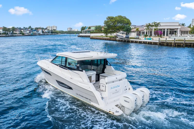 Slide: The Image of 2024 Regal 38 XO yacht cruising on a scenic waterfront with luxury homes. - 3