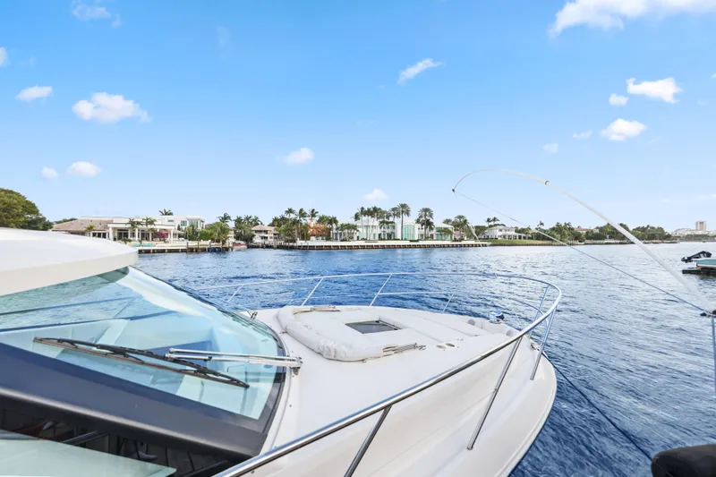 Slide: The Image of 2024 Regal 38 XO yacht cruising on a sunny day near waterfront homes. - 36