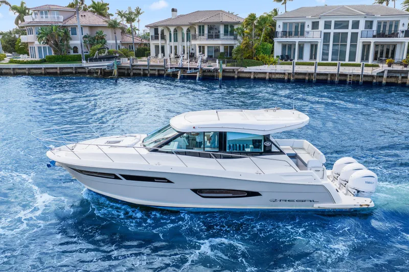 Slide: The Image of 2024 Regal 38 XO yacht cruising on blue water near luxury waterfront homes. - 45