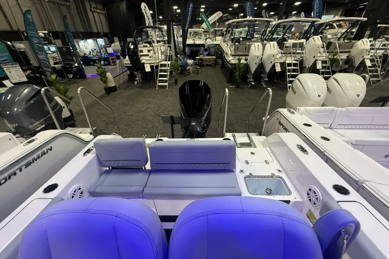 Slide: The Image of 2026 Sportsman Heritage 231 Center Console at a boat show, showcasing seating and engine area. - 7