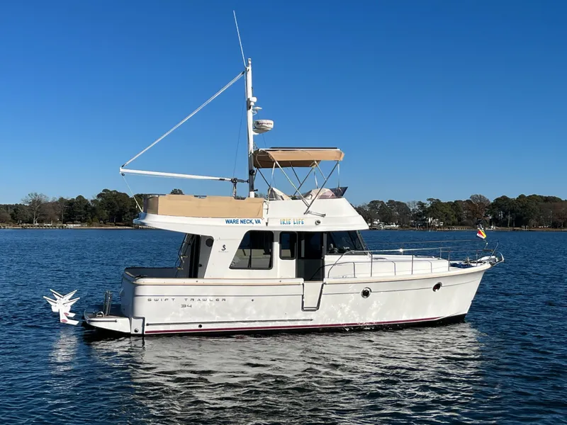 Slide: The Image of 2013 Beneteau Swift Trawler 34 on calm water under clear blue sky. - 1