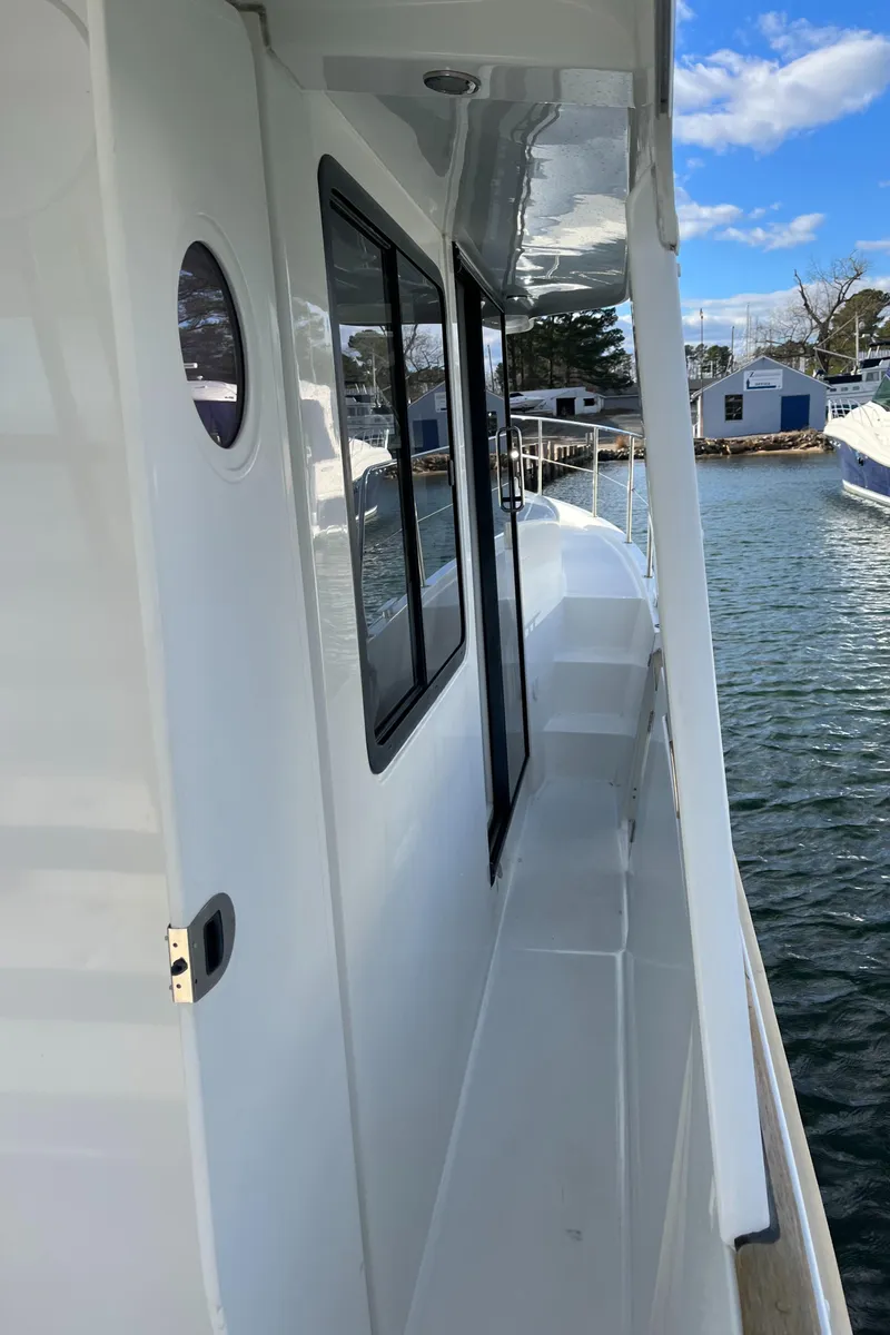 Slide: The Image of 2013 Beneteau Swift Trawler 34, side deck view, docked by calm waters. - 21