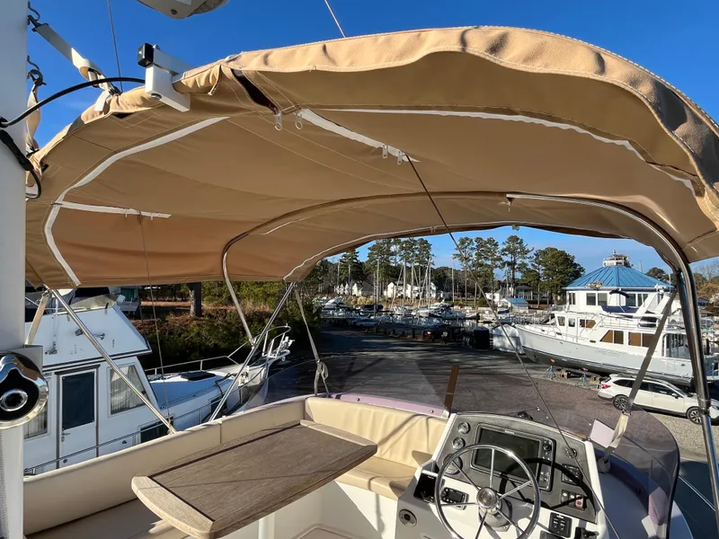 Slide: The Image of Flybridge of 2013 Beneteau Swift Trawler 34 with helm and seating, docked at marina. - 34