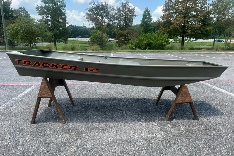 The Image of 2026 Tracker Grizzly 12 Jon boat displayed on wooden stands in a parking lot. - 0