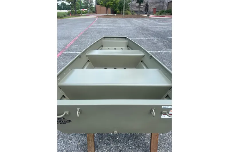 Slide: The Image of 2026 Tracker Grizzly 12 Jon boat displayed on wooden stands in a parking lot. - 10