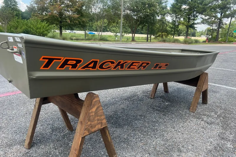 Slide: The Image of 2026 Tracker Grizzly 12 Jon boat on wooden stands in a parking lot. - 2