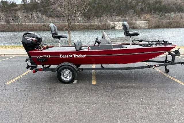Slide: The Image of 2026 Tracker Bass Tracker Classic XL boat on trailer by a river. - 80