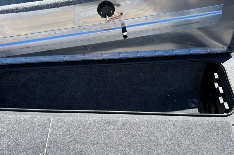 Slide: The Image of Open storage compartment in 2026 Tracker Pro Team 190 boat, featuring carpeted interior. - 36