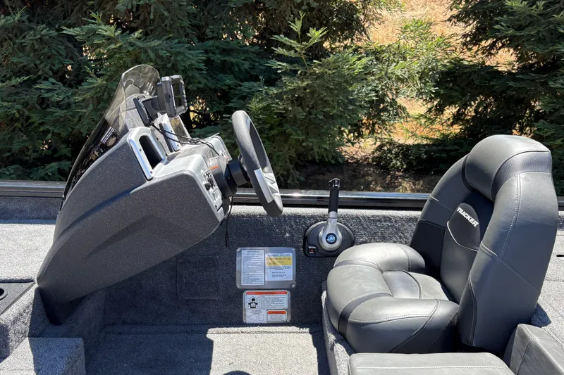 Slide: The Image of 2026 Tracker Pro Team 190 boat interior with steering wheel and seat, surrounded by trees. - 16