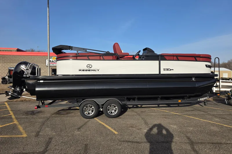 The Image of 2026 Regency 230 DL pontoon boat on trailer in parking lot, side view. - 1