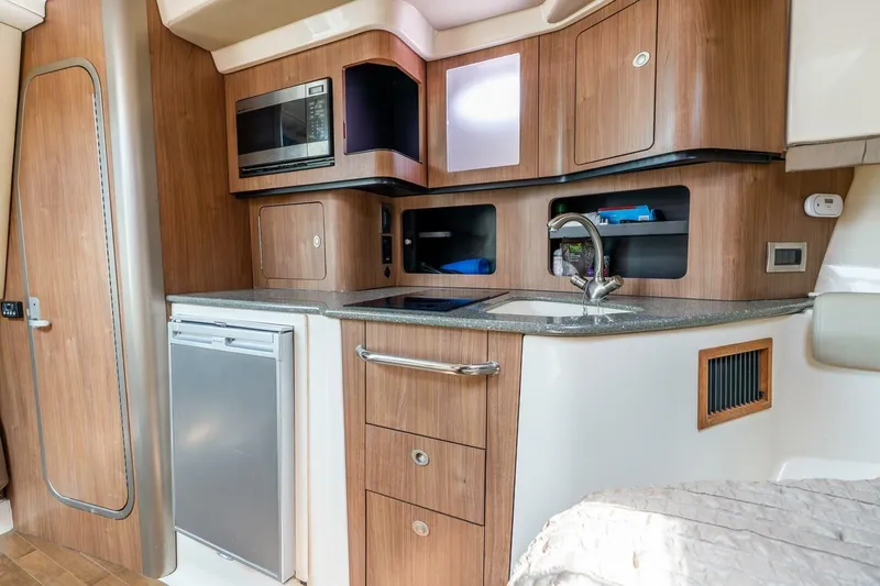 Slide: The Image of 2012 Boston Whaler 345 Conquest interior kitchen with wood cabinetry and modern appliances. - 16