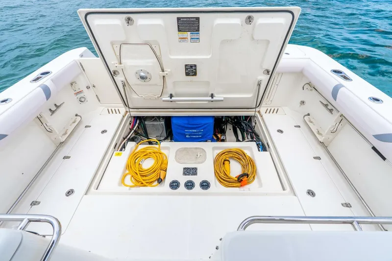 Slide: The Image of 2012 Boston Whaler 345 Conquest boat deck with open storage compartment and coiled yellow cable. - 25