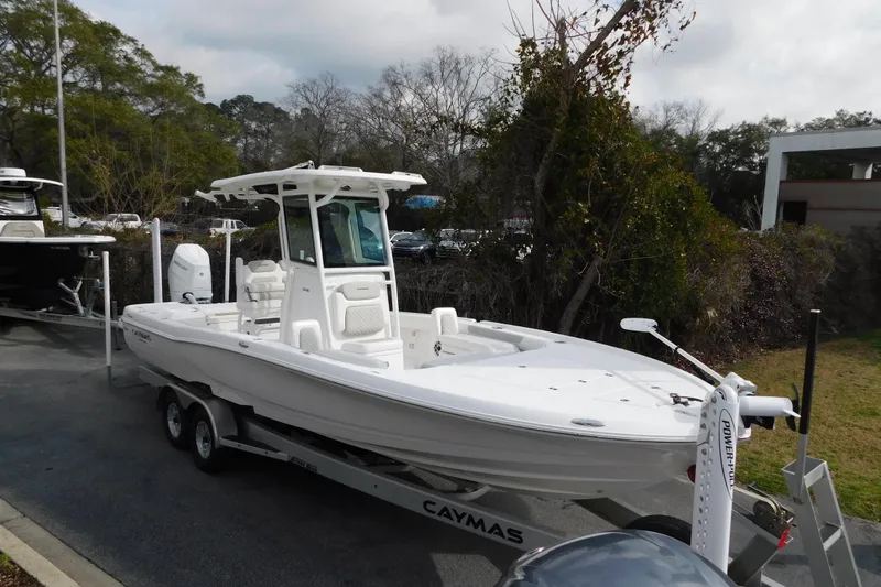 Slide: The Image of 2023 Caymas 28 HB boat on trailer, parked outdoors, surrounded by trees. - 10