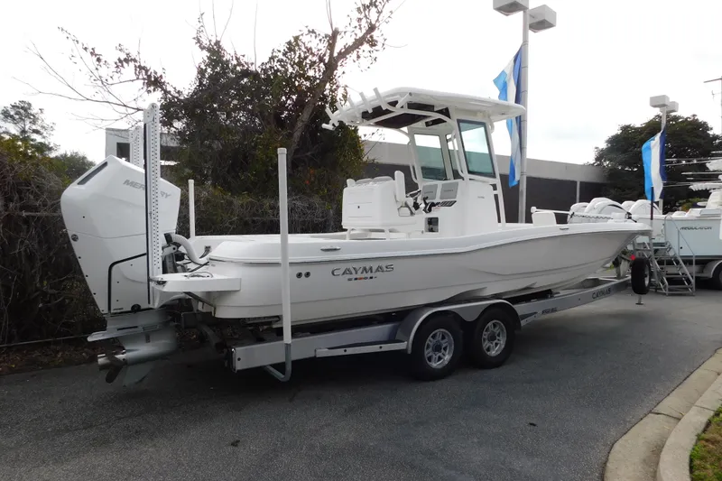 Slide: The Image of 2023 Caymas 28 HB boat on trailer, displayed outdoors with trees and flags. - 9