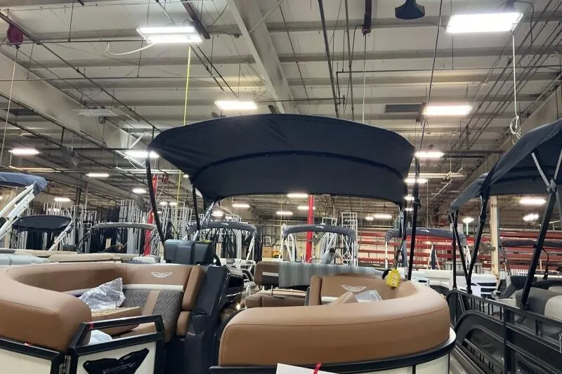 Slide: The Image of 2026 Bennington 22 MSBSF pontoon boat in a showroom with tan seating and black canopy. - 17