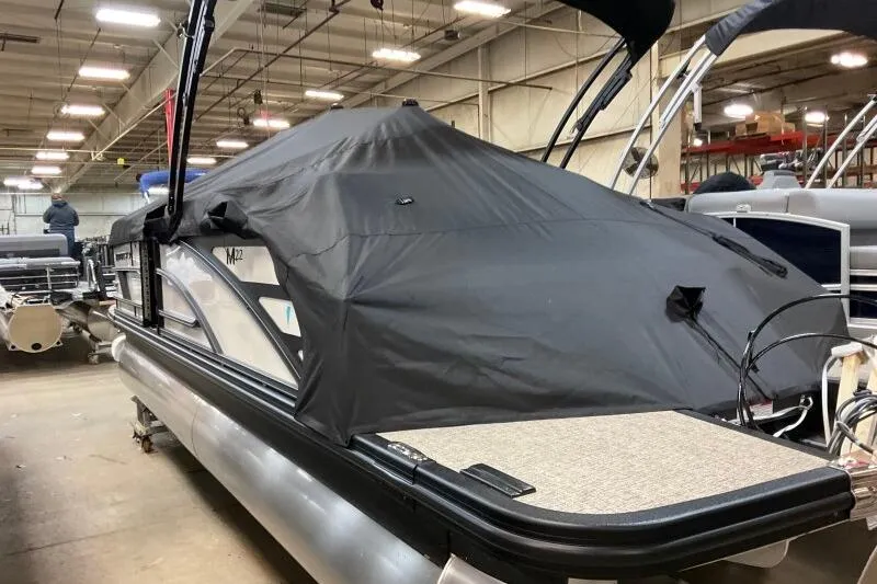Slide: The Image of 2026 Bennington 22 MSBSF pontoon boat with black cover in a warehouse setting. - 20