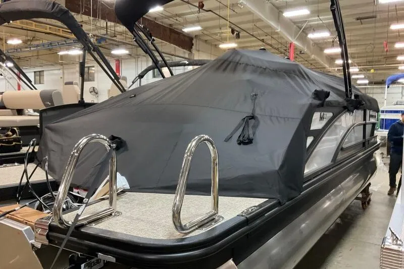 Slide: The Image of 2026 Bennington 22 MSBSF pontoon boat with black cover in a showroom. - 21