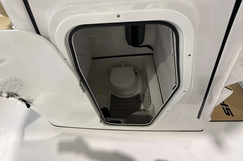 Slide: The Image of 2026 Sportsman Heritage 261 Center Console boat interior with open door revealing compact toilet. - 34