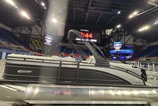 Slide: The Image of 2026 Harris Solstice 230 CWDH pontoon boat displayed indoors at an event. - 3