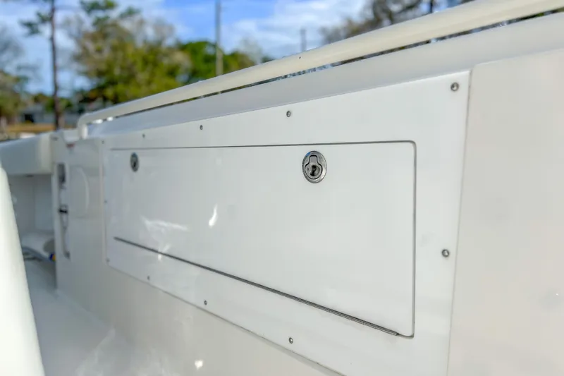 Slide: The Image of Edgewater 318CC 2011 boat storage compartment with lock, white exterior, outdoor setting. - 14