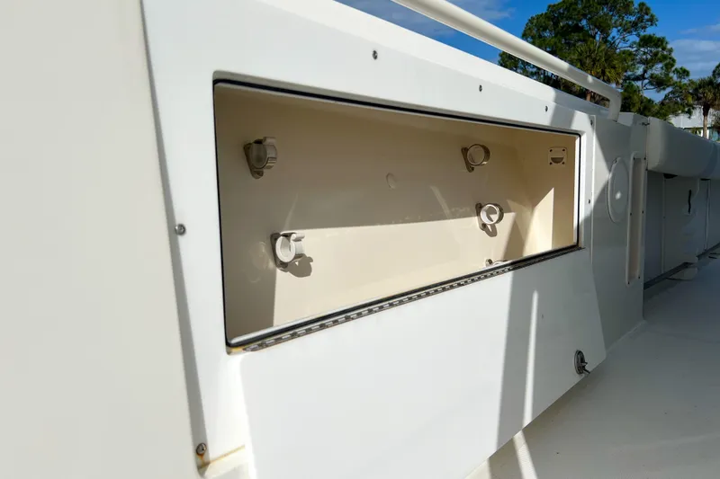 Slide: The Image of Edgewater 318CC 2011 boat storage compartment with open hatch, white interior, and sunny background. - 17
