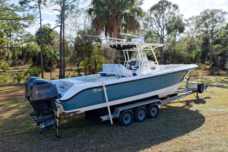 Slide: The Image of 2011 Edgewater 318CC boat on trailer, surrounded by trees and grass. - 29