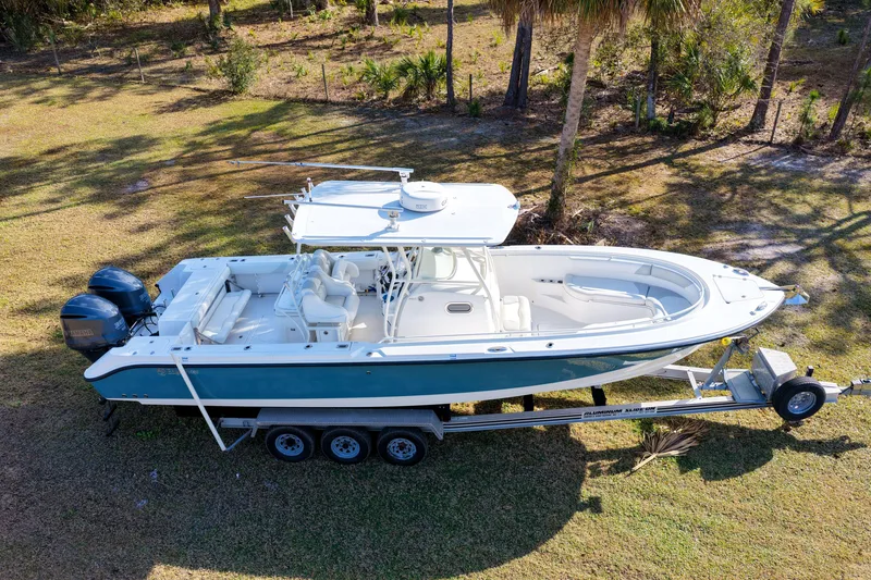 Slide: The Image of 2011 Edgewater 318CC boat on trailer, parked on grassy area, with dual outboard engines. - 30