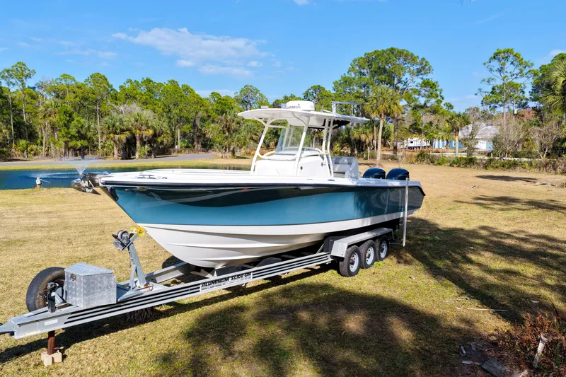 Slide: The Image of 2011 Edgewater 318CC boat on trailer, parked on grassy area near trees and pond. - 33