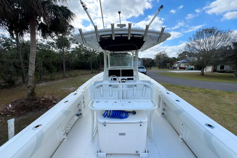 Slide: The Image of 2011 Edgewater 318CC boat with fishing rod holders and storage, parked outdoors. - 5