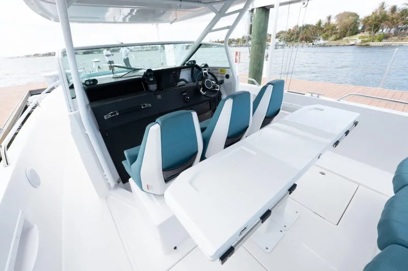 Slide: The Image of 2021 Axopar 37 Sun-Top boat interior with helm, seating, and table on the water. - 14