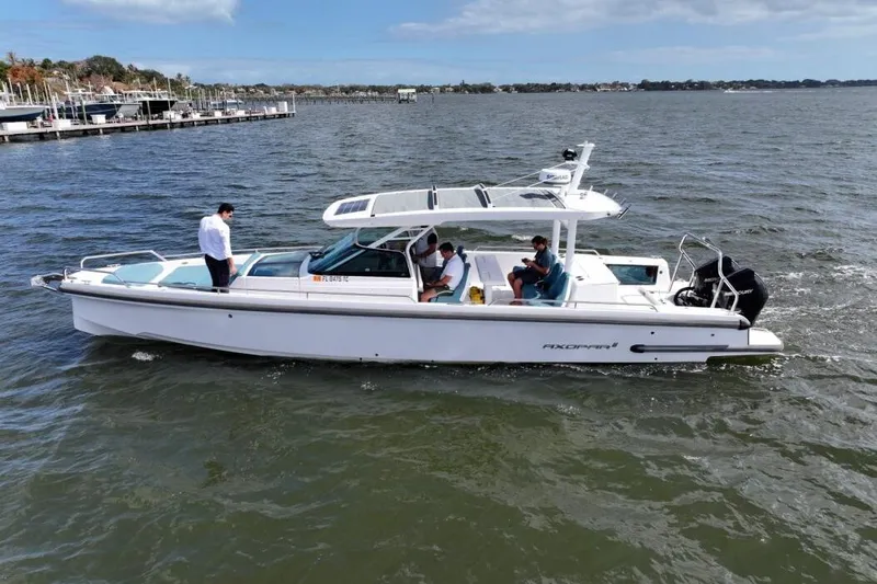 Slide: The Image of 2022 Axopar 37 Sun-Top boat cruising on a calm lake with passengers onboard. - 4