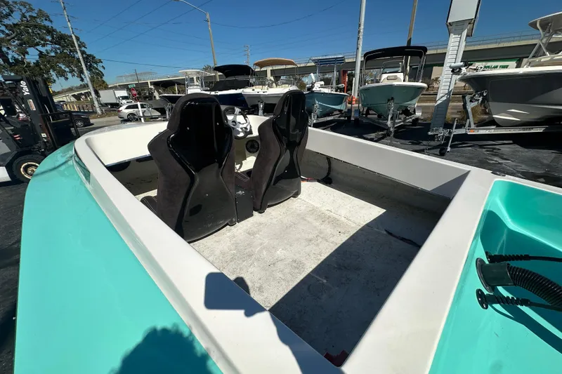 Slide: The Image of 2022 Lightning 18 boat interior with black seats, parked outdoors under clear sky. - 11