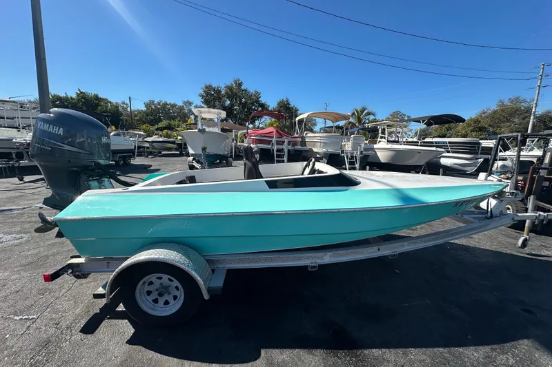 Slide: The Image of Turquoise 2022 Lightning 18 boat on trailer, parked in marina with Yamaha outboard motor. - 6