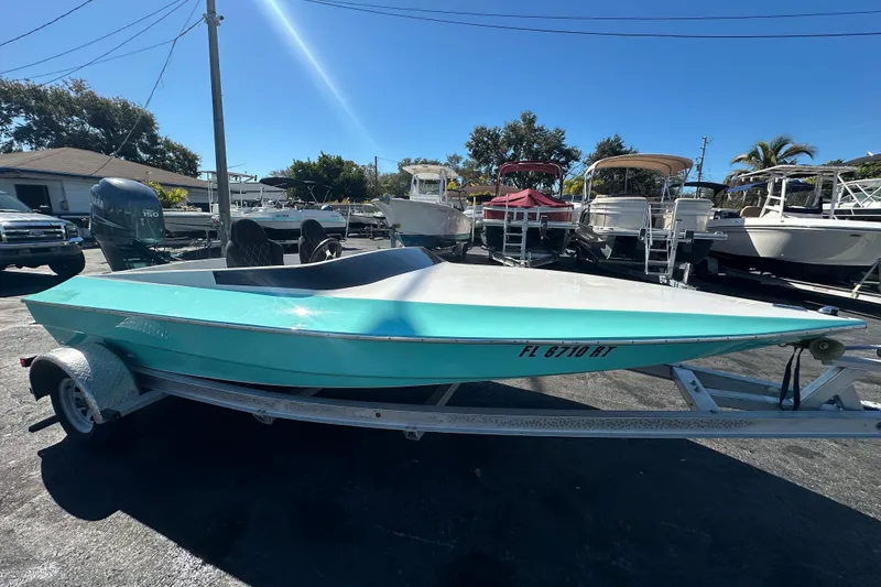 Slide: The Image of 2022 Lightning 18 boat in turquoise on trailer, parked in marina under clear blue sky. - 7