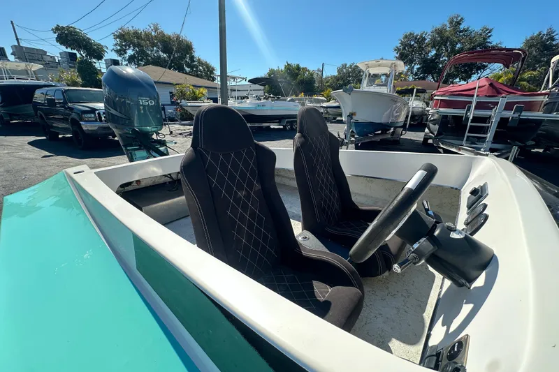 Slide: The Image of 2022 Lightning 18 boat interior with steering wheel and seats, parked outdoors. - 8