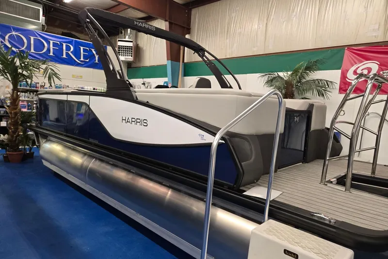 Slide: The Image of 2026 Harris Sunliner 230 pontoon boat displayed indoors with modern design and sleek features. - 2