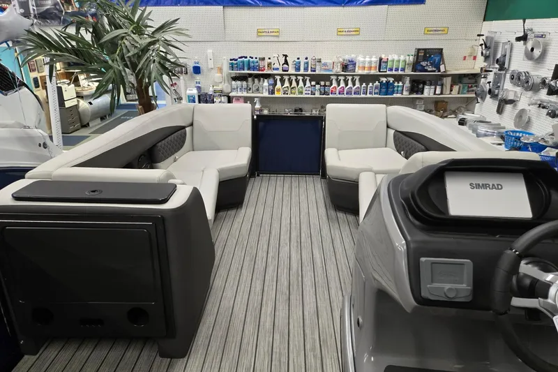 Slide: The Image of 2026 Harris Sunliner 230 boat interior with seating and control panel in a showroom. - 30
