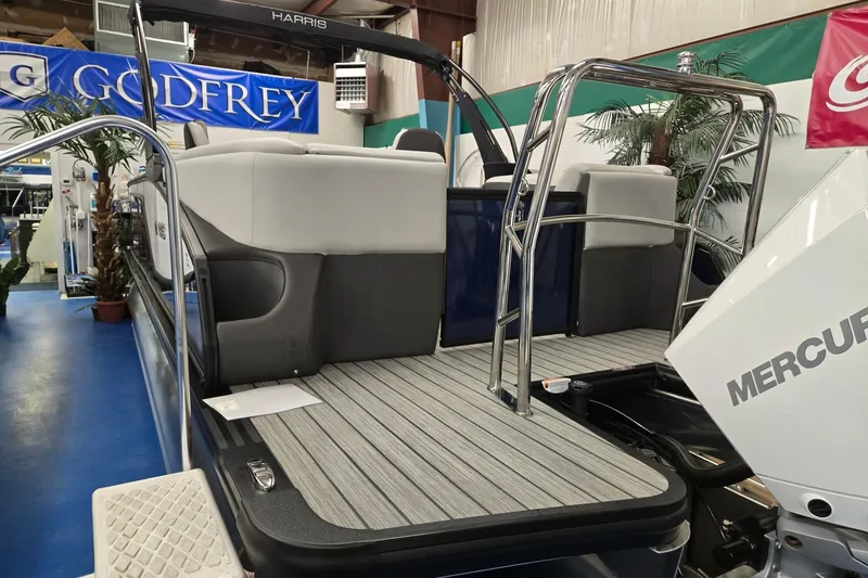 Slide: The Image of 2026 Harris Sunliner 230 pontoon boat with Mercury engine, showcased indoors. - 4
