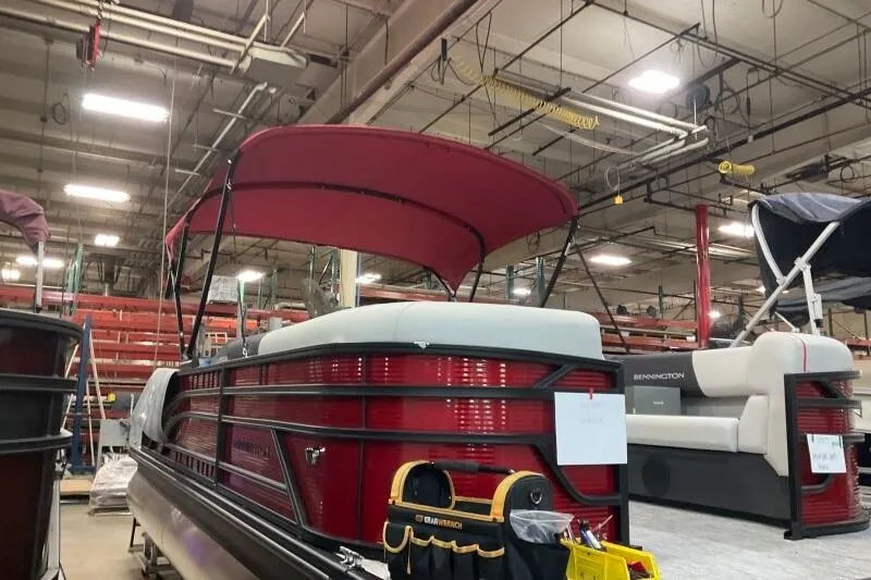 Slide: The Image of 2026 Bennington 22 SSBSF pontoon boat in a factory setting with red canopy. - 19