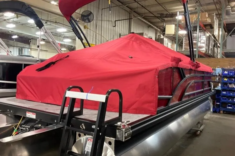 Slide: The Image of 2026 Bennington 22 SSBSF pontoon boat with red cover in a warehouse setting. - 22
