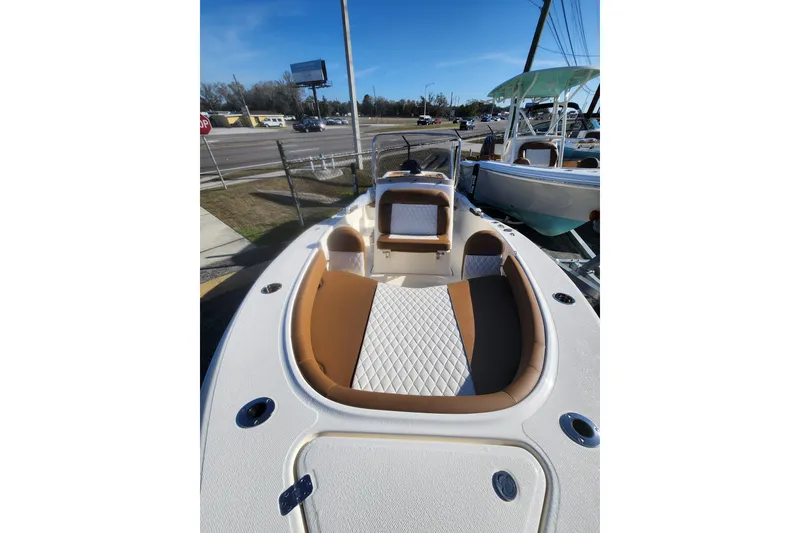 Slide: The Image of 2026 Pioneer 180 Islander boat with tan and white seating, parked outdoors. - 10