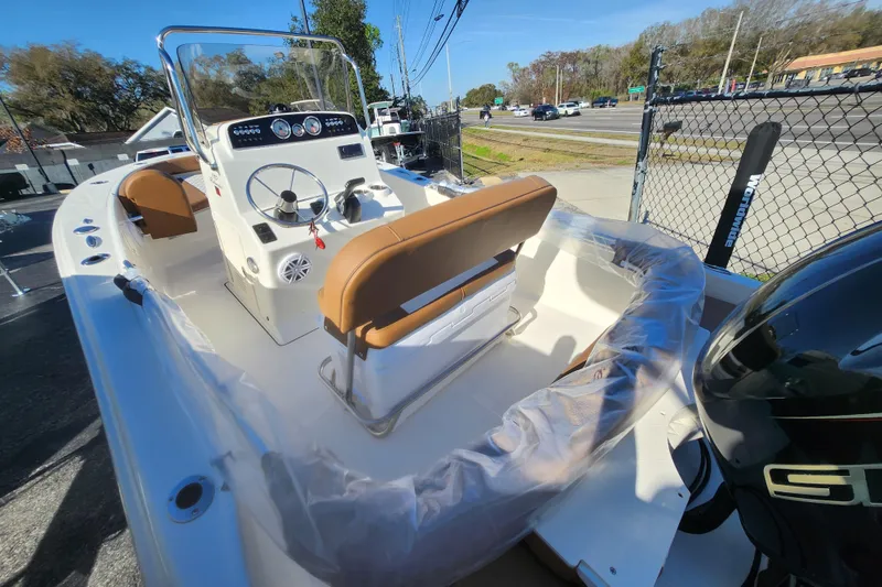 Slide: The Image of 2026 Pioneer 180 Islander boat with brown seating and modern dashboard, parked outdoors. - 3