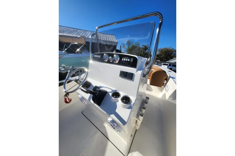 Slide: The Image of 2026 Pioneer 180 Islander boat console with steering wheel and gauges under clear blue sky. - 6
