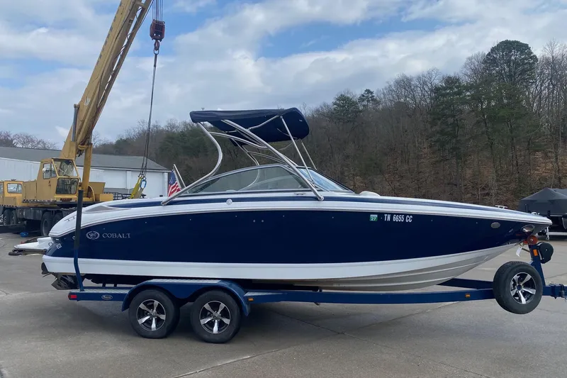 Slide: The Image of 2008 Cobalt 222 boat on trailer, blue and white, with crane in background. - 4